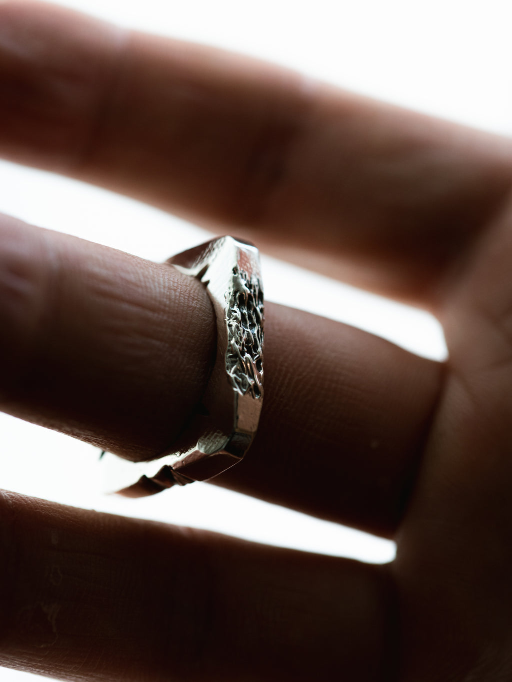 Silver ring on a finger with a blurred background